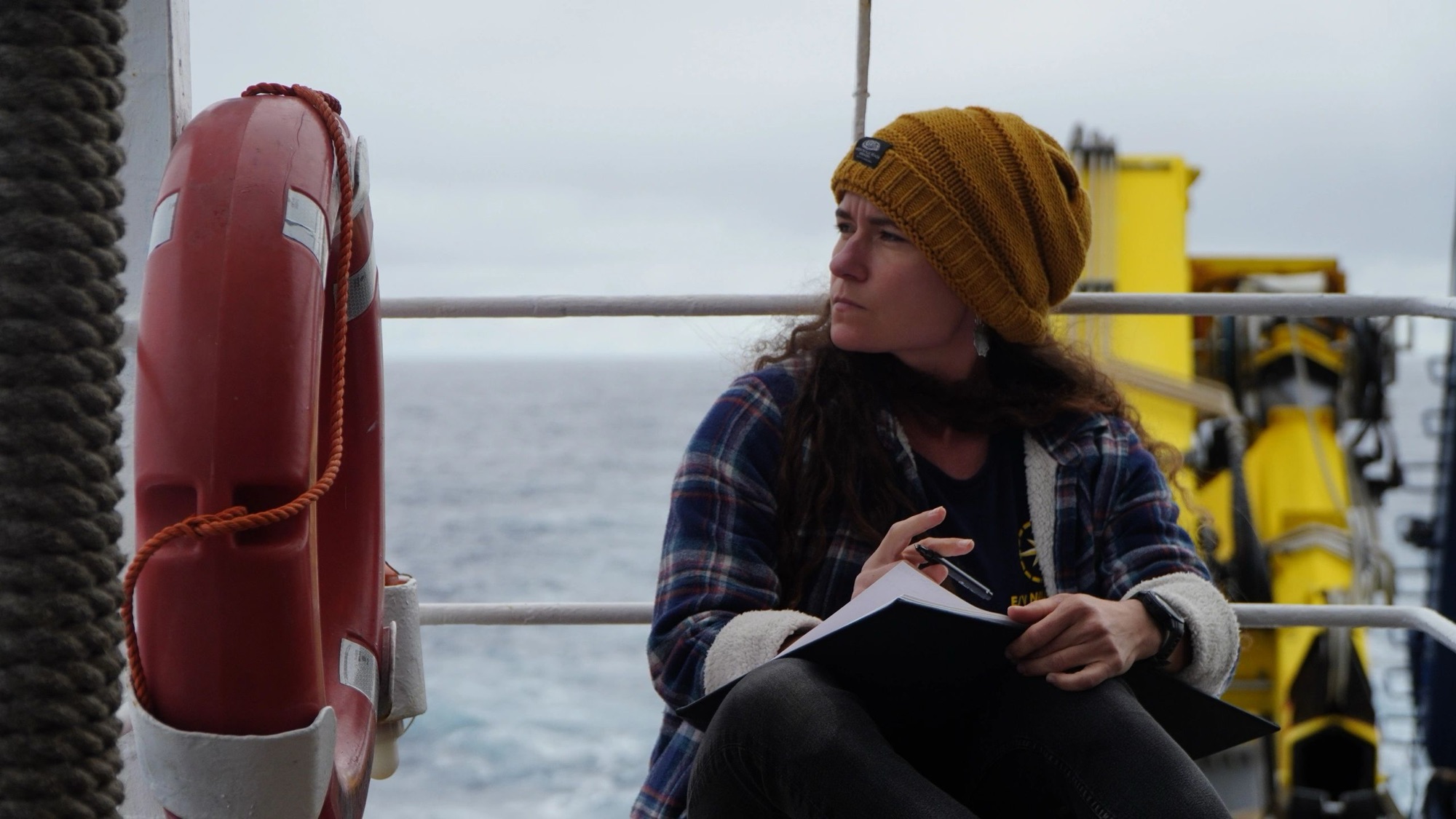 Researcher taking field notes on the deck of a ship