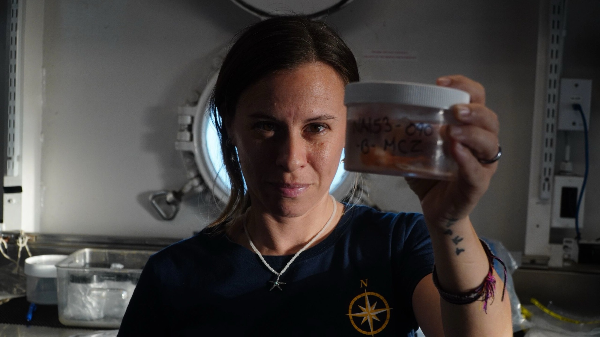 Marine scientist holding up a specimen jar aboard a research vessel